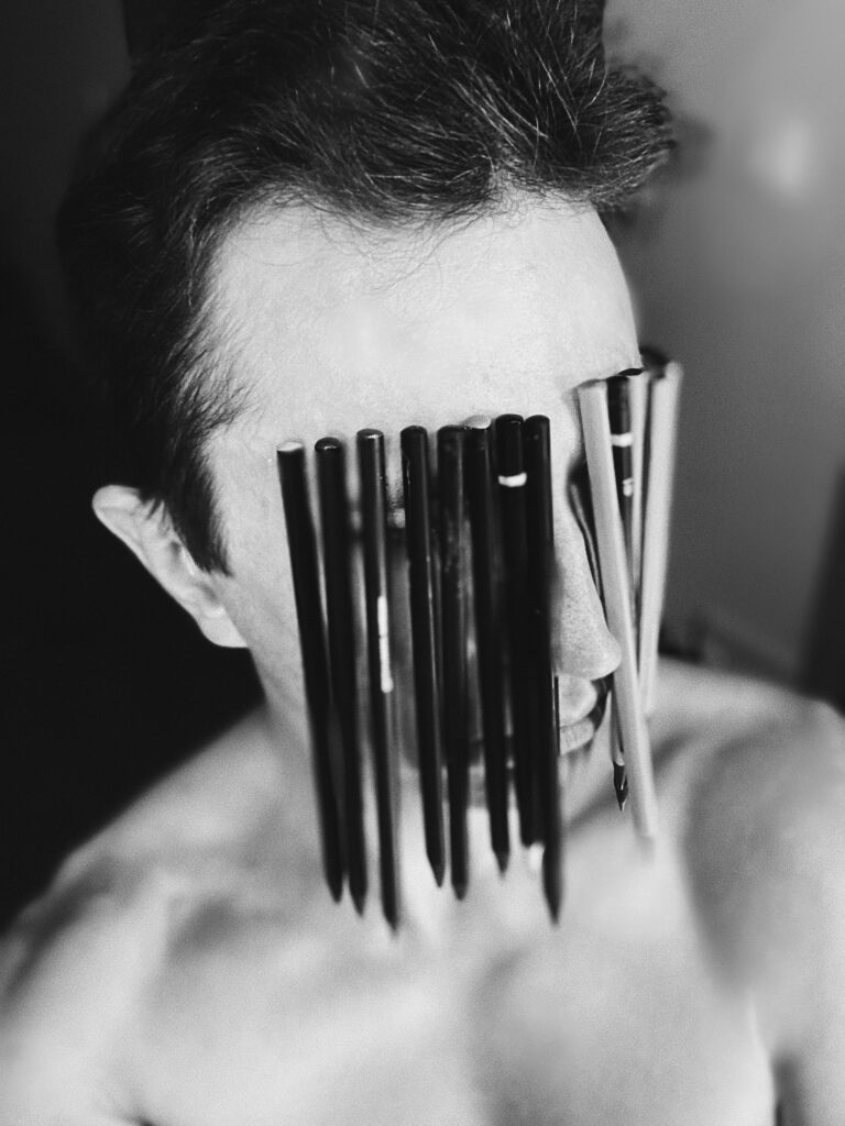 A black and white artistic portrait featuring pencils creatively covering a face.